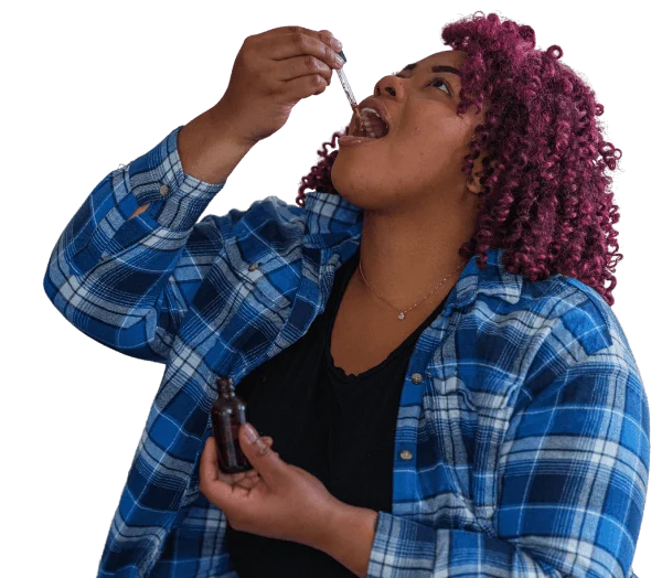 Imagem com fundo transparente de uma mulher negra com cabelos cacheados na cor roxa, usando uma blusa xadrez azul e branco, tomando óleo de cannabis com o conta-gotas.